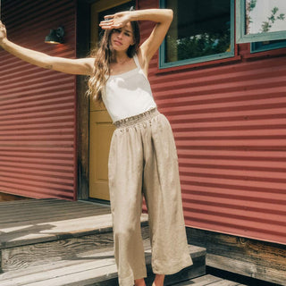 Woman posing on wooden steps in front of a red corrugated metal building.