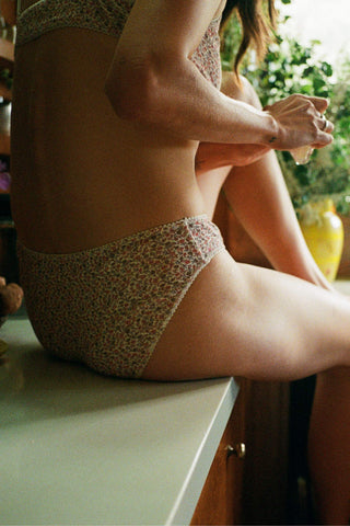 Person wearing a patterned underwear sitting on a surface with a blurred background