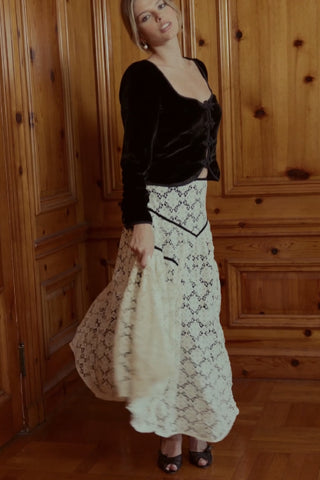 Video still of a woman in a black top and white skirt dancing