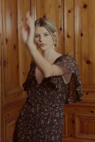 video still of a woman in a flowery brown dress dancing