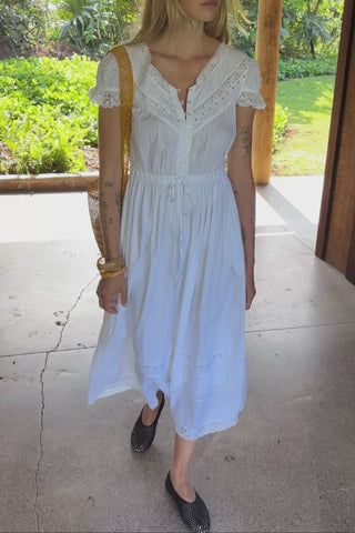 Woman wearing a white dress with lace details with a yellow bag on her shoulder