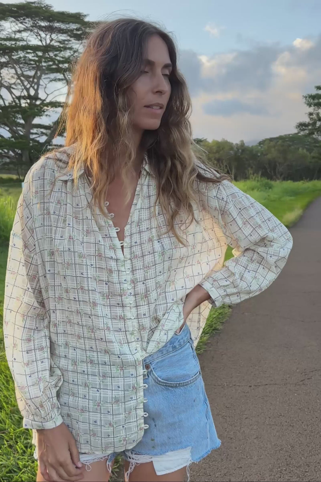 Video of a woman wearing a checkered shirt with floral patterns.