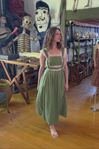 Woman in a green dress walking in an interior setting.