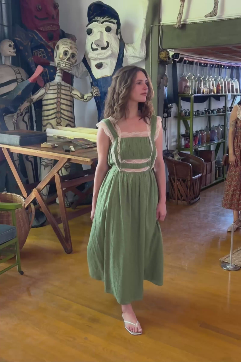 Woman in a green dress walking in an interior setting.