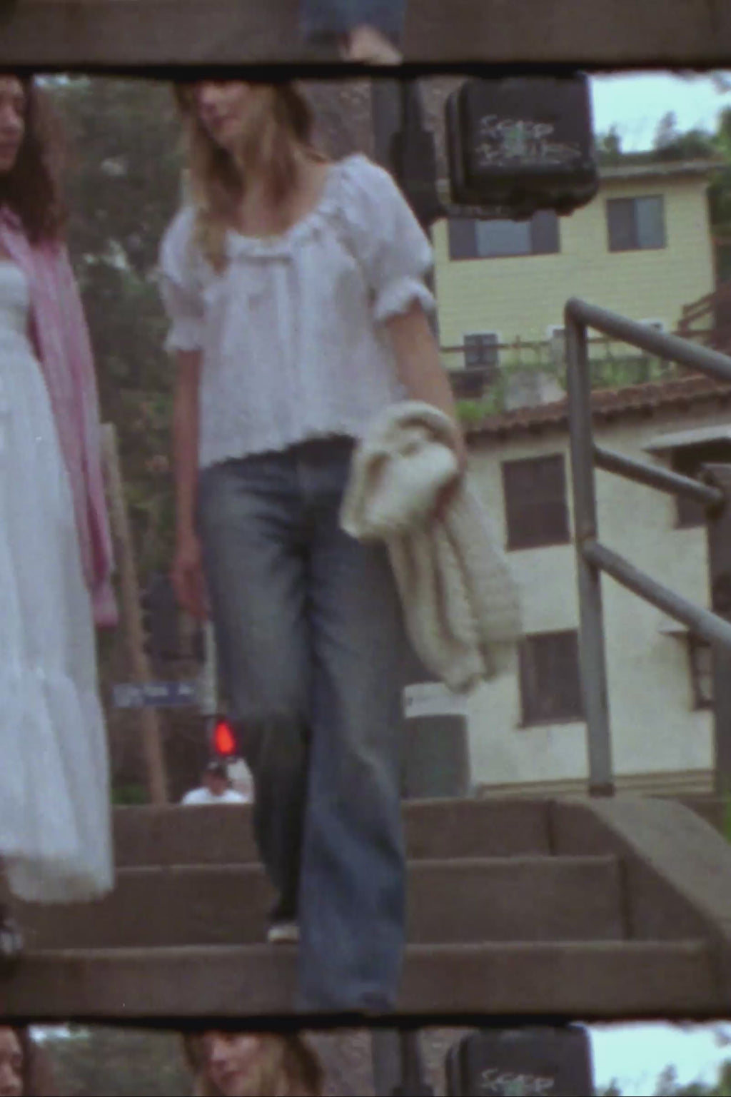 woman wearing a white blouse and wide brim hat crossing a road