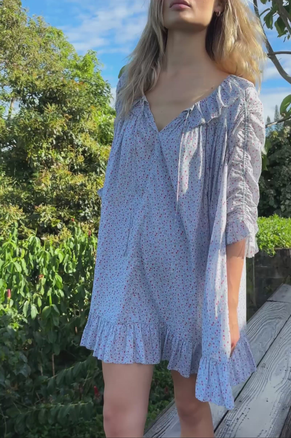 A video of a woman wearing a light blue floral patterned dress with a close up of details