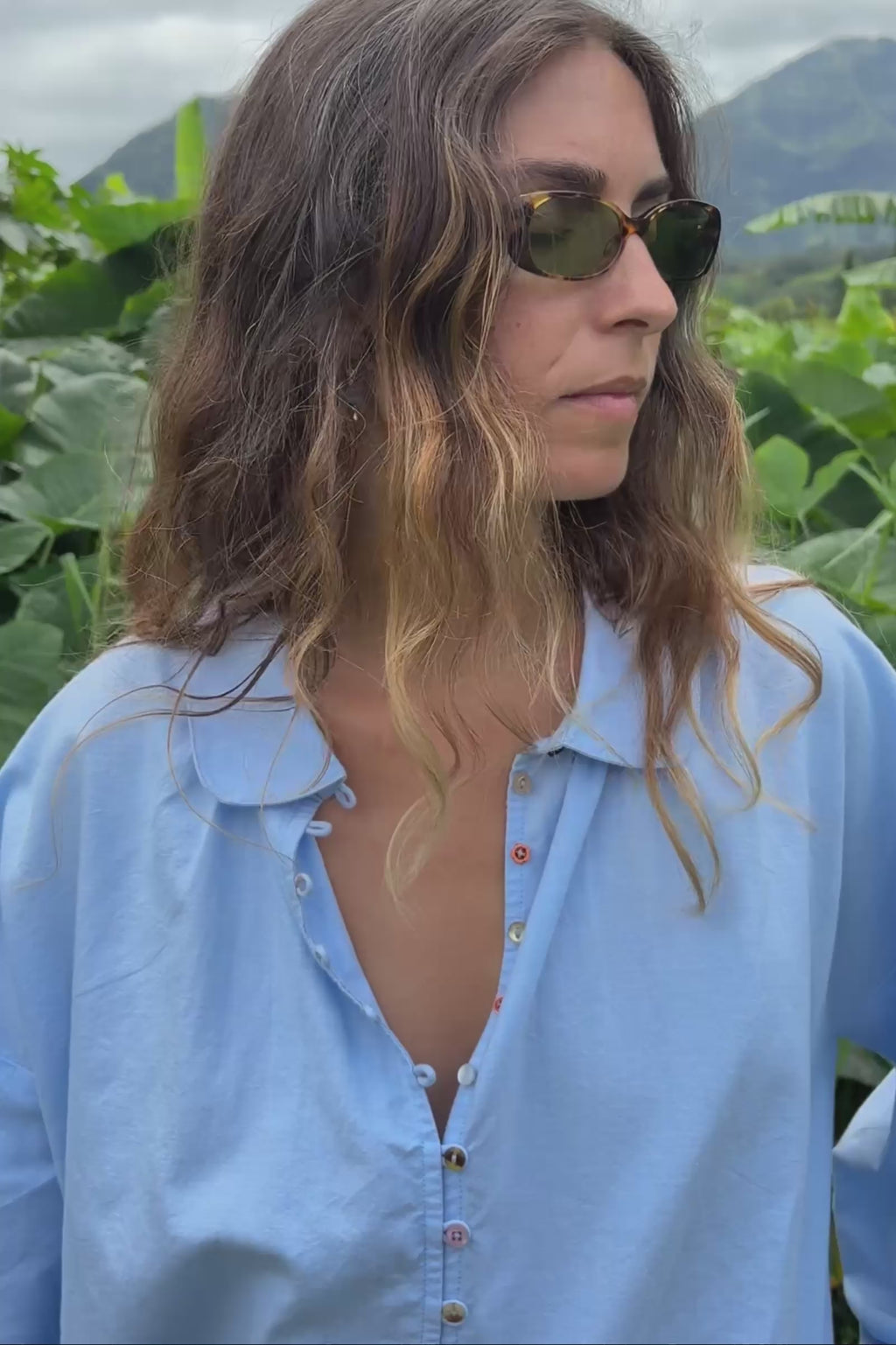 Video of a woman wearing a light-blue chambray button down shirt
