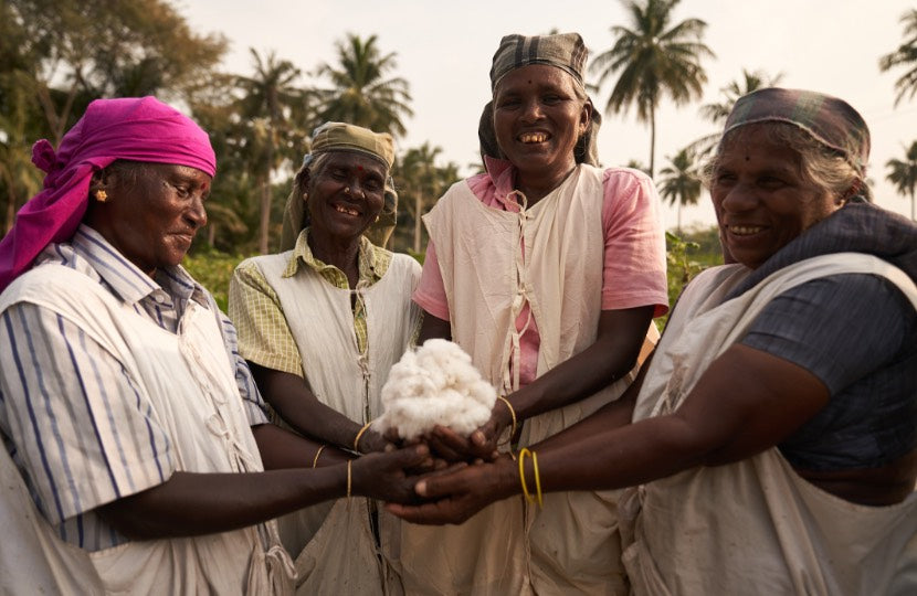 Four smiling women holding cotton in a field